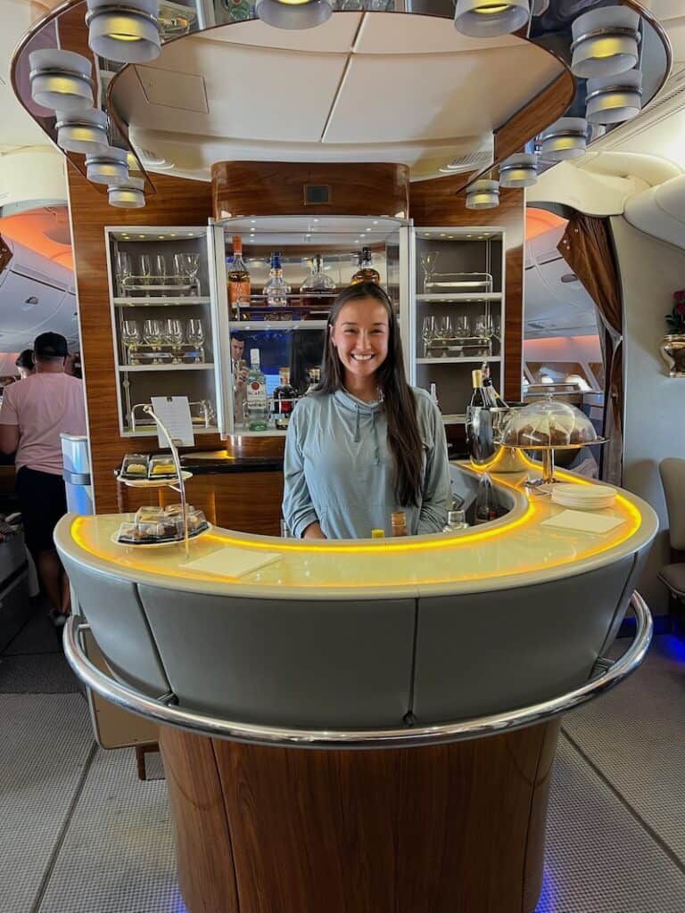 A woman standing behind the business class bar onboard an Emirates airbus A380. 