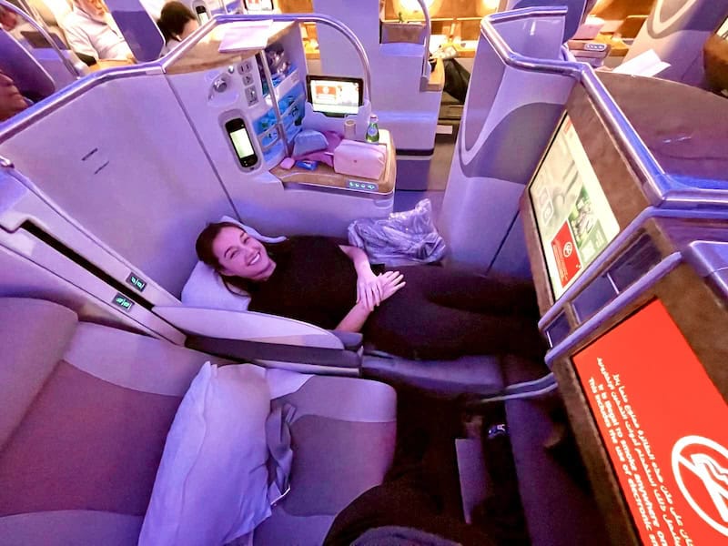 Woman laying flat on an Emirates business class seat on an airbus A380. 