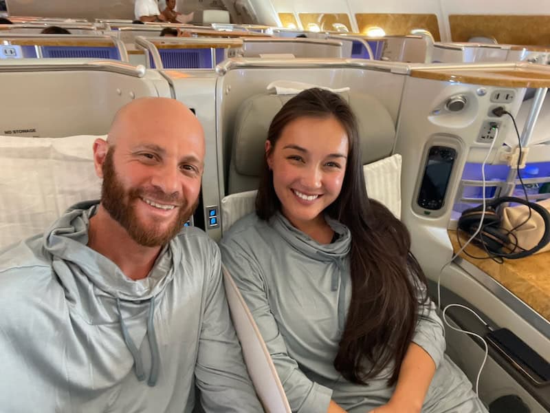 Couple sitting in Emirates business class seats onboard an airbus A380. 